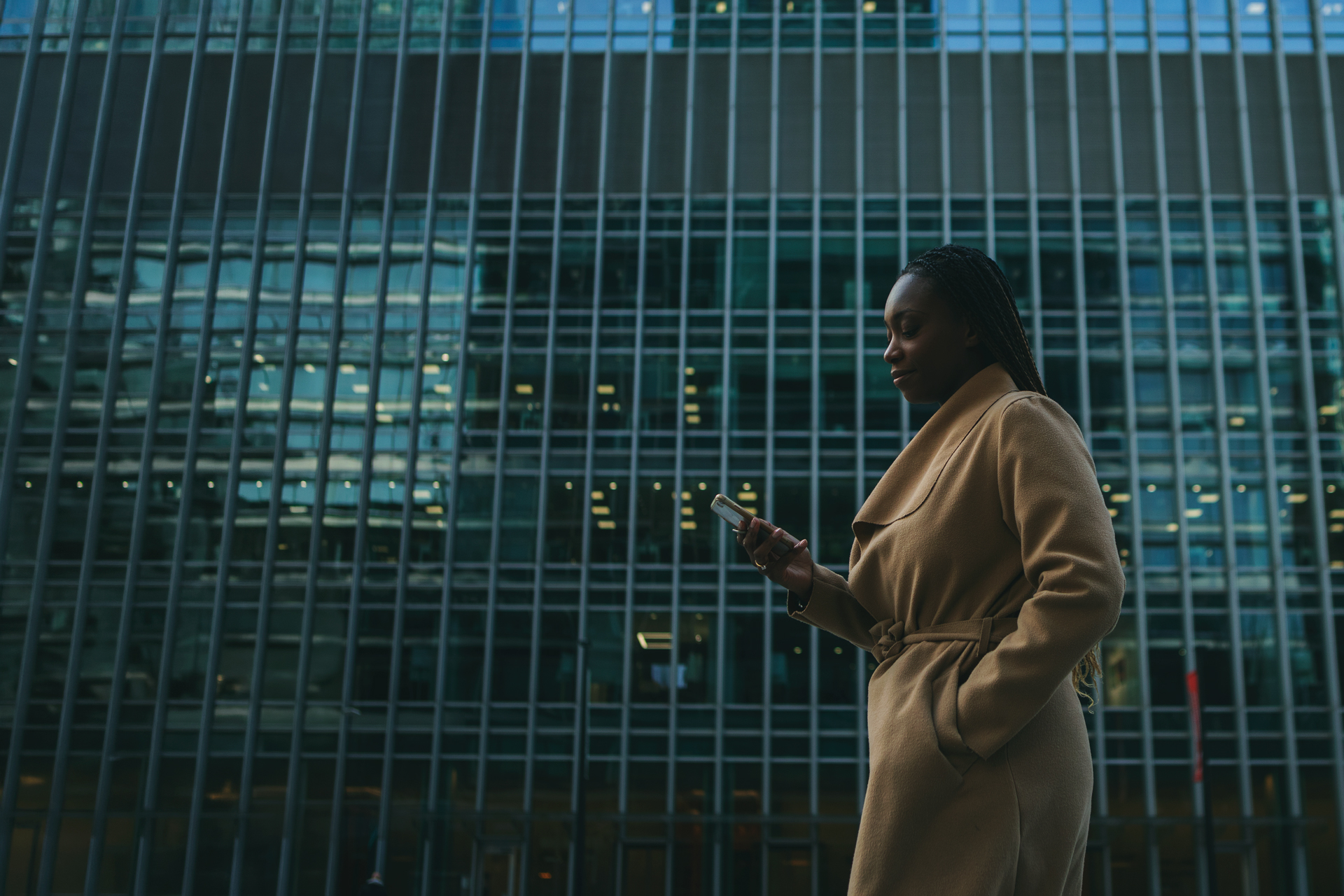 Mulher usando o celular em frente a um prédio